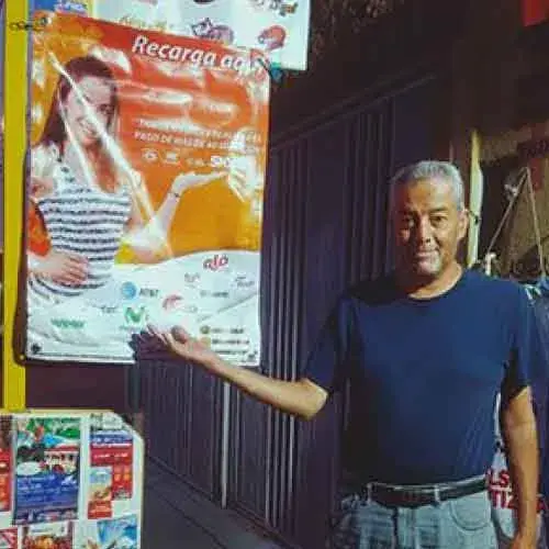 hombre mayor señalando una lona en su negocio vende pines para aumentar las ventas de su negocio en aguascalientes